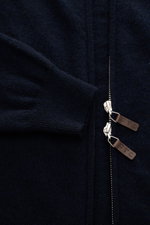 Close-up shot of FTC Cashmere cardigan navy showing fine knit fabric, ribbed sleeve cuff, concealed two-way zipper with leather FTC logo pulls from above.