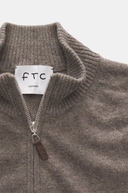 Nahaufnahme der FTC Cashmere Strickjacke taupe meliert von oben mit geripptem Stehkragen, verdecktem Zwei-Wege-Reißverschluss und Leder-Logo-Detail.