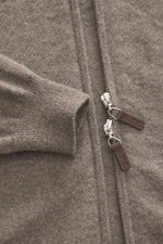 Nahaufnahme der FTC Cashmere Strickjacke taupe meliert in Regular Fit, perspektivisch auf den verdeckten Zwei-Wege-Reißverschluss mit Leder-Logo-Zipper und geripptem Stehkragen, weicher Fair-Trade-Cashmere mit feinem Strickbild und flexiblen Rippbündchen,