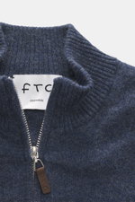 Nahaufnahme aus schräger Draufsicht der FTC Cashmere Strickjacke graublau meliert mit geripptem Stehkragen, verdecktem Zwei-Wege-Reißverschluss und Leder-Logo am Zipper, gefertigt aus weichem Fair-Trade-Cashmere mit feinem Strickbild, Regular Fit, OEKO-TE