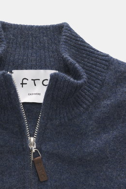 Nahaufnahme aus schräger Draufsicht der FTC Cashmere Strickjacke graublau meliert mit geripptem Stehkragen, verdecktem Zwei-Wege-Reißverschluss und Leder-Logo am Zipper, gefertigt aus weichem Fair-Trade-Cashmere mit feinem Strickbild, Regular Fit, OEKO-TE