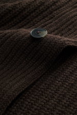 Nahaufnahme des dunkelbraunen Closed Cardigan mit Patentstrick aus reiner Wolle, weichem Griff, grobem Strickbild, Knopf, Schalkragen und Rippbündchen.