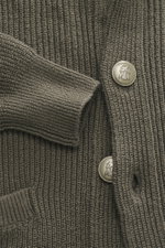 Nahaufnahme des graugrünen Brunello Cucinelli Cardigans, detailreich von oben fotografiert, mit geripptem Patent-Strickmuster und Wappen-Knöpfen.