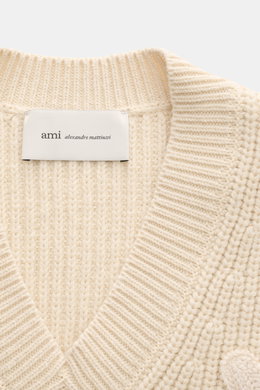 Close-up front view of the Ami Paris V-Neck Pullunder sand showing its chunky ribbed knit in wool and cotton, soft texture, and the sewn-on 'Ami' logo. <p>Layering-Piece von AMI PARIS: Der ikonische Pullunder mit V-Neck und typischem 'Ami'-Logo im College