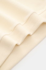 Close-up image of the hem and ribbed cuff of the 04651/ A trip in a bag Rundhalspullover creme, showing its soft fleece texture and creamy wool-cotton blend, photographed from a side angle. <p>Legeres Layering Piece: Der Rundhalspullover von 04651/ A TRIP
