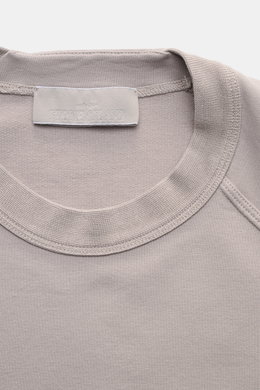 Close-up top view of Stone Island Sweatshirt 'Ghost Piece' grau showing round neckline, elastic cotton fabric, tonal compass badge on sleeve, raglan sleeves, and comfortable cuffs.

Description: <p>STONE ISLAND bietet mit diesem Sweatshirt aus elastischer