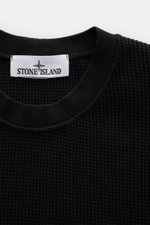 Close-up front view of Stone Island Rundhalspullover 'Waffle' schwarz in black waffle knit cotton with ribbed round neckline and brand label. Basic Piece mit Twist: Dieser Pullover im Waffelstrick von STONE ISLAND wird zur idealen Grundlage moderner Freiz