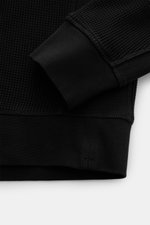 Close-up image of the Stone Island Rundhalspullover 'Waffle' schwarz, showing the cuff and hem from a top-down perspective. <p>Basic Piece mit Twist: Dieser Pullover im Waffelstrick von STONE ISLAND wird zur idealen Grundlage moderner Freizeitlooks und lä