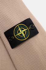 Stone Island Rundhalspullover 'Waffle' taupe shown in close-up from a side angle, highlighting the waffle-knit cotton fabric and the black compass badge on the upper arm. <p>Basic Piece mit Twist: Dieser Pullover im Waffelstrick von STONE ISLAND wird zur 