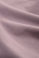 Nahaufnahme des weichen, schweren Baumwolljerseys in Mauve des Stone Island Longsleeve mauve, perspektivisch leicht schräg fotografiert.