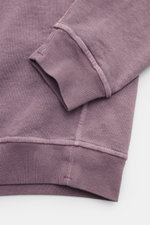 Nahaufnahme des Stone Island Rundhals-Sweatshirts „Washed Sweat“ flieder von oben, mit weichem Baumwollstoff, Washed-Effekt, Nahtkante und Rippbündchen.