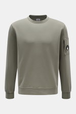 Front view of a C.P. Company Sweatshirt salbei in a slim fit, light garment-dyed pure cotton with a round neckline, ribbed cuffs, and a zipped sleeve pocket featuring the brand's signature lens detail. <article class="text-token-text-primary w-full focus:
