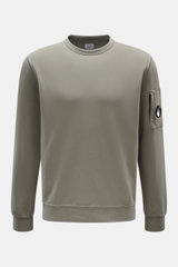 Front view of a C.P. Company Sweatshirt salbei in a slim fit, light garment-dyed pure cotton with a round neckline, ribbed cuffs, and a zipped sleeve pocket featuring the brand's signature lens detail. <article class="text-token-text-primary w-full focus: