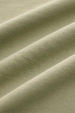 Close-up front view of the olive green C.P. Company Sweatshirt oliv fabric showing its soft, lightweight, garment-dyed pure cotton texture with fine knit detail and slight folds. <article class="text-token-text-primary w-full focus:outline-none [--shadow-