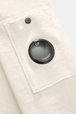 Nahaufnahme des C.P. Company Rundhals-Sweatshirts creme, Perspektive auf die Oberarmtasche mit Druckknopf und Lens-Detail.