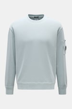 C.P. Company Sweatshirt rauchblau, frontale Ansicht, Rundhalsausschnitt, Oberarmtasche mit Linsen-Detail, reine Baumwolle, Regular Fit.