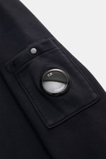 C.P. Company Sweatshirt navy in Nahaufnahme von der Ärmeltasche mit markantem Linsen-Detail und Druckknopf, reine Baumwolle.