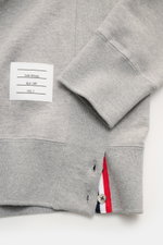 Nahaufnahme des Thom Browne Rundhals-Sweatshirts grau meliert von der Ärmel- und Saumseite, aus reiner Baumwolle mit weichem Griff, Rippbündchen, geknöpften Saumschlitzen mit Grosgrain-Besatz und labeltypischen Kontraststreifen am Ärmel, inklusive rückwär