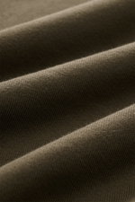 Nahaufnahme des olivfarbenen Stoffes eines C.P. Company Sweatshirt oliv, stückgefärbt, leichte Baumwolle mit weichem Griff.