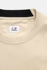 Nahaufnahme des Rundhalsausschnitts und des C.P. Company Sweatshirt sand, fotografiert aus frontaler Perspektive, aus reiner Baumwolle mit feinem Rippbündchen.
