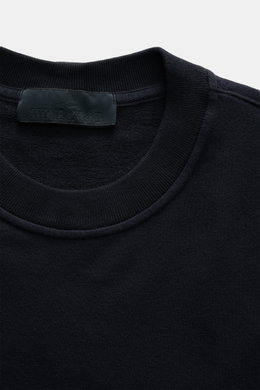 Nahaufnahme des Rundhalsausschnitts vom Stone Island Sweatshirt 'Ghost Piece' navy, elastische Baumwollqualität, weicher Griff, Regular Fit, tonales Kompass-Badge am Ärmel, fotografiert von oben.