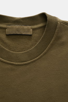 Stone Island Sweatshirt 'Ghost Piece' oliv, Detailaufnahme von oben, Rundhalsausschnitt, tonales Kompass-Badge, elastische Baumwollqualität, Regular Fit, weicher Griff.