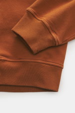 Nahaufnahme des Stone Island Sweatshirts 'Ghost Piece' rostbraun, Fokus auf elastische Rippbündchen und weiche Baumwollqualität.