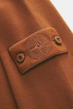 Nahaufnahme des tonalen Kompass-Badges auf dem Ärmel des Stone Island Sweatshirts 'Ghost Piece' rostbraun aus elastischer Baumwolle.