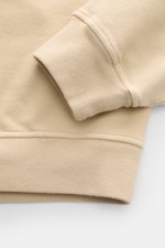 Nahaufnahme des Stone Island Sweatshirt 'Ghost Piece' beige, seitliche Perspektive auf elastisches Baumwoll-Sweatshirt mit weichem Griff, Rippbündchen und tonalem Kompass-Badge.