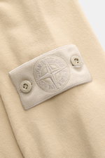 Nahaufnahme des tonalen Kompass-Badges am Ärmel des Stone Island Sweatshirt 'Ghost Piece' beige, aus elastischer Baumwolle.