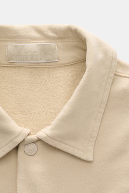 Nahaufnahme des beigen Stone Island Longsleeve Sweat-Poloshirts 'Ghost Piece' aus weichem Baumwollsweat mit Polokragen und STONE ISLAND-Patch, frontal fotografiert.