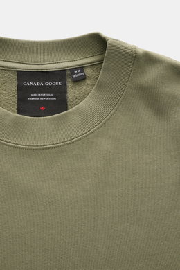 Close-up top view of Canada Goose Sweatshirt 'Loon' grey green showing crew neckline, ribbed cuffs, and woven label inside collar.

Description: <p>Comfort 24/7 offers the lightweight 'Loon' sweatshirt made of pure cotton by CANADA GOOSE, which complement