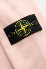 Close-up of the Stone Island Crew Neck Sweatshirt 'Basic Sweat' rose showing the black compass badge on the upper arm, photographed from a top angle. Timeless basic piece: The STONE ISLAND sweatshirt is the ideal basic for casual leisure looks and evolves