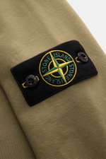Stone Island Rundhals-Sweatshirt 'Basic Sweat' oliv, Nahaufnahme des Kompass-Badges am Oberarm, weiches Baumwollmaterial, Rippbündchen.