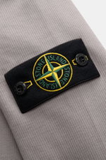 Close-up front view of the Stone Island R-Neck Longsleeve grey showing fine ribbed knit cotton fabric, compass badge, and button details.

Description: <p>Autumn essential: The long sleeve by STONE ISLAND combines a distinctive ribbed knit structure with 