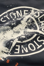 Close-up view of the Stone Island Sweatshirt 'Print' dunkelgrau showcasing its soft dark gray cotton fabric and distinctive white compass logo print with splattered paint effect on the front.

<div class="relative w-full overflow-visible">
<section class=