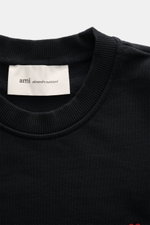 A close-up front view of the Ami Paris Crewneck Sweatshirt black showing the ribbed crew neckline and fabric label inside. Comfortable basic: The AMI PARIS sweatshirt made of pure cotton is the ideal companion for sporty looks. Sweat made of pure cotton, 