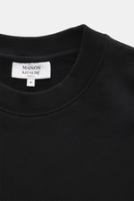 Nahaufnahme des Rundhalsausschnitts und Labels des Maison Kitsuné Sweatshirt schwarz, Sweat aus reiner Baumwolle, weicher Griff, Slim Fit, typisches Fuchs-Patch.