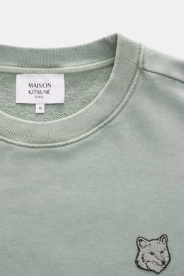 Nahaufnahme des mintgrünen Maison Kitsuné Sweatshirts aus reiner Baumwolle mit Rundhalsausschnitt und Fuchs-Patch auf der Brust, weicher Griff.