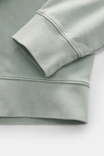Nahaufnahme des mintgrünen Maison Kitsuné Sweatshirts von schräg oben, Fokus auf Ärmel und Bündchen aus weicher Baumwolle mit Oversized Fit.