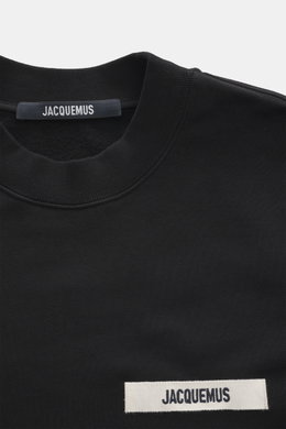 Nahaufnahme des Jacquemus Sweatshirts 'Gros Grain' schwarz von schräg oben, Sweat aus reiner Baumwolle, schwere Qualität, softe Innenseite, markante Overlock-Nähte, Regular Fit, Rundhalsausschnitt, Grosgrain mit Logo-Stitching auf der Brust, komfortable R