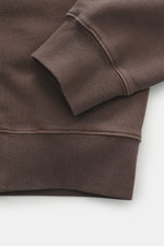 Nahaufnahme des dunkelbraunen Jacquemus Sweatshirt 'Gros Grain' Ärmels in leichter Schräge, Sweat aus reiner Baumwolle, schwere Qualität, softe Innenseite, markante Overlock-Nähte, Regular Fit, Rundhalsausschnitt, Grosgrain mit Logo-Stitching auf der Brus