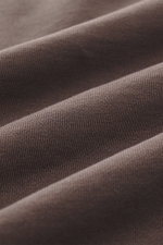 Nahaufnahme des Jacquemus Sweatshirts 'Gros Grain' dunkelbraun aus reiner Baumwolle, schwere Qualität, softe Innenseite, Regular Fit, Rundhalsausschnitt, Grosgrain mit Logo-Stitching, markante Overlock-Nähte und komfortable Rippbündchen, Stoffdetail in Fa