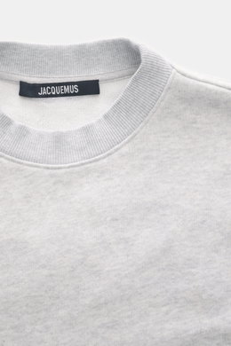 Nahaufnahme des Rundhalsausschnitts eines Jacquemus Sweatshirts 'Torneo' hellgrau meliert, Sweat aus reiner Baumwolle, softe Innenseite, Regular Fit, Patch am Saum, Logo-Stitching auf der Rückseite, komfortable Rippbündchen, fotografiert von oben.