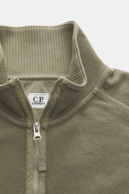 Nahaufnahme des C.P. Company Sweat-Troyer taupe von oben, Sweat aus reiner Baumwolle, weicher Griff, Regular Fit, Troyer-Kragen mit Reißverschluss, aufgesetzte Tasche am Oberarm, labeltypisches Linsen-Detail, flexible Rippbündchen.