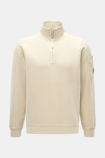 Frontale Nahaufnahme des C.P. Company Sweat-Troyer sand, Sweat aus reiner Baumwolle, weicher Griff, Regular Fit, Troyer-Kragen mit Reißverschluss, aufgesetzte Tasche am Oberarm, labeltypisches Linsen-Detail, flexible Rippbündchen.