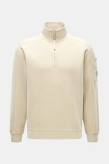 Frontale Nahaufnahme des C.P. Company Sweat-Troyer sand, Sweat aus reiner Baumwolle, weicher Griff, Regular Fit, Troyer-Kragen mit Reißverschluss, aufgesetzte Tasche am Oberarm, labeltypisches Linsen-Detail, flexible Rippbündchen.