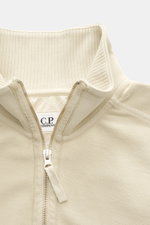 Nahaufnahme des C.P. Company Sweat-Troyer sand von schräg oben, Sweat aus reiner Baumwolle, weicher Griff, Regular Fit, Troyer-Kragen mit Reißverschluss, aufgesetzte Tasche am Oberarm, labeltypisches Linsen-Detail, flexible Rippbündchen.