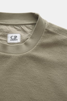 Nahaufnahme des Rundhalsausschnitts vom C.P. Company Sweatshirt salbei, Inside-Out-Design aus reiner Baumwolle mit weichem Griff.