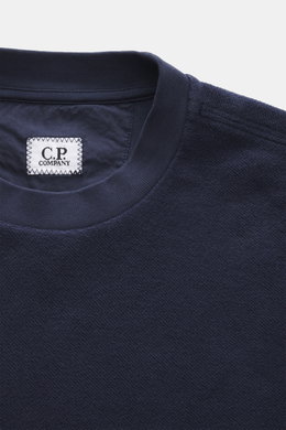Nahaufnahme des Rundhalsausschnitts und Labels eines C.P. Company Sweatshirt navy aus reiner Baumwolle mit softem Griff, fotografiert von oben.